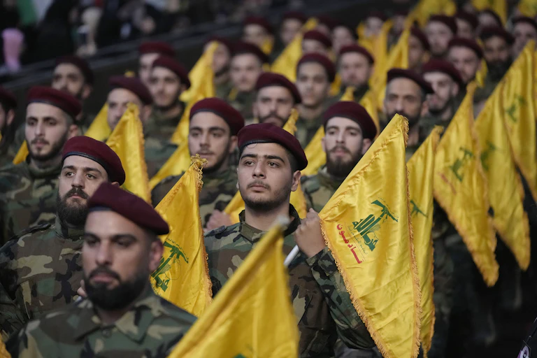 Men in military fatigues and red berets carrying yellow flags.