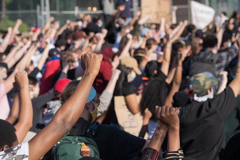 People at a protest raising their hands with their fists clenched.