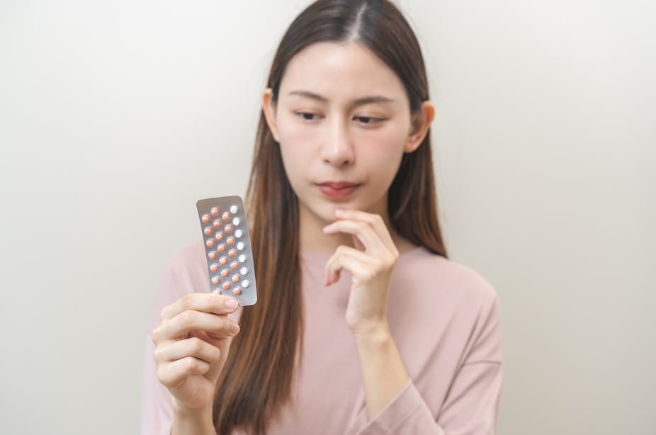 A young woman looks inquiringly at her pack of birth control pills.