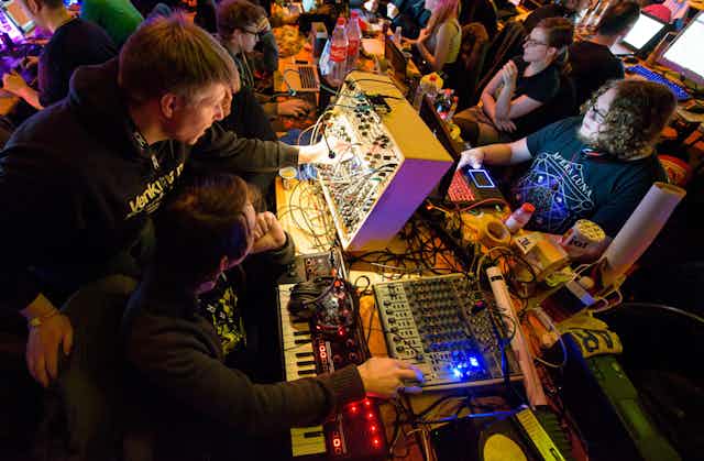 Technology enthusiasts work on modular synthesizers at an analogue tech festival