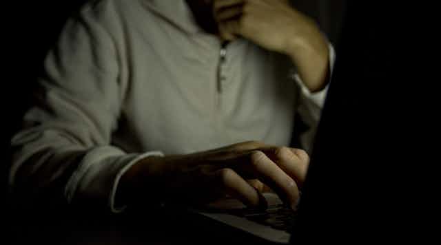 Anonymous man in shadow typing on a laptop