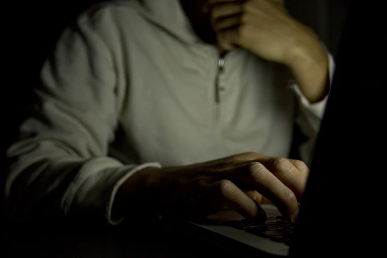 Anonymous man in shadow typing on a laptop