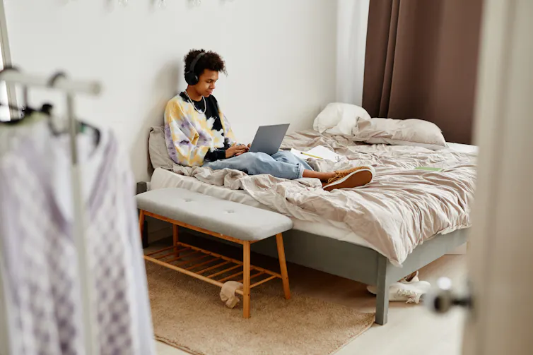 Image of a teenager on a bed with a laptop.