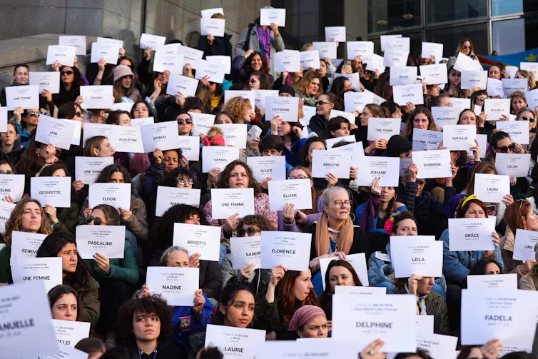 Women holding up white signs with women's names written on them.