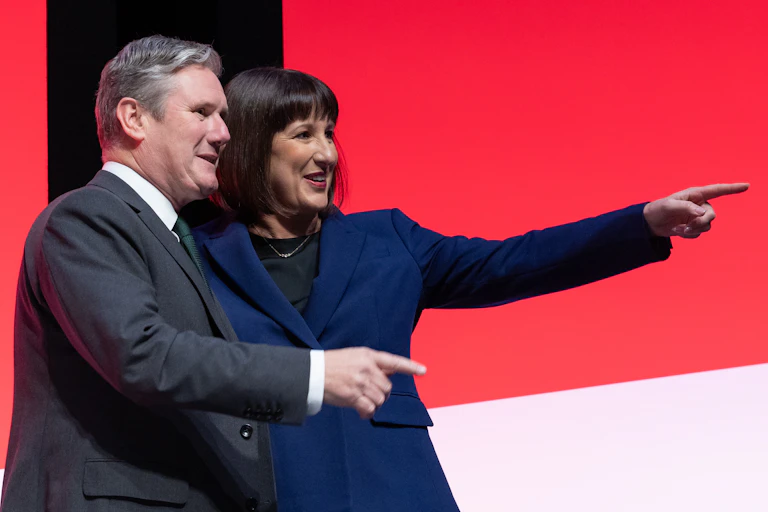 Keir Starmer and Rachel Reeves both pointing and smiling at something off camera