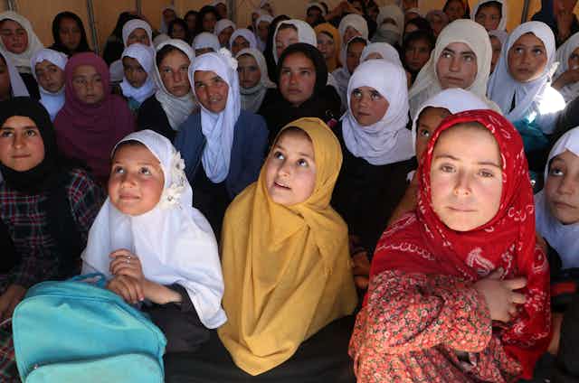 Girls in headscarves look up, presumably toward their teacher. 