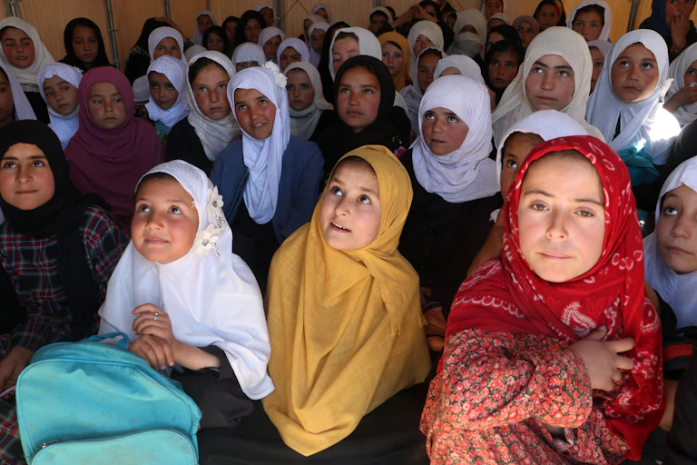 Girls in headscarves look up, presumably toward their teacher.