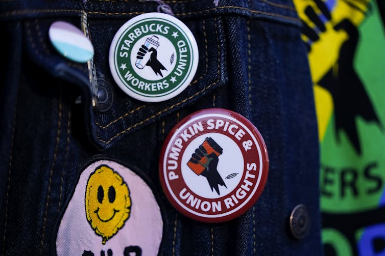 Assorted pro-union Starbucks pins and patches affixed to denim.