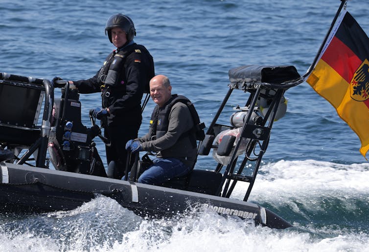 Men stand on a speedboat.