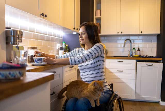 woman in wheelchair makes coffee in her kitchen