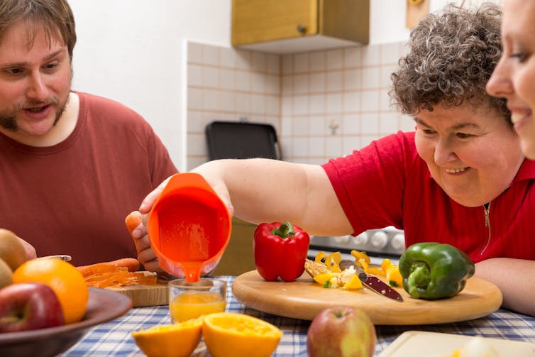 Three people at table share food preparation