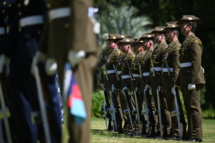 A row of Australian soldiers stand next to each other outdoors