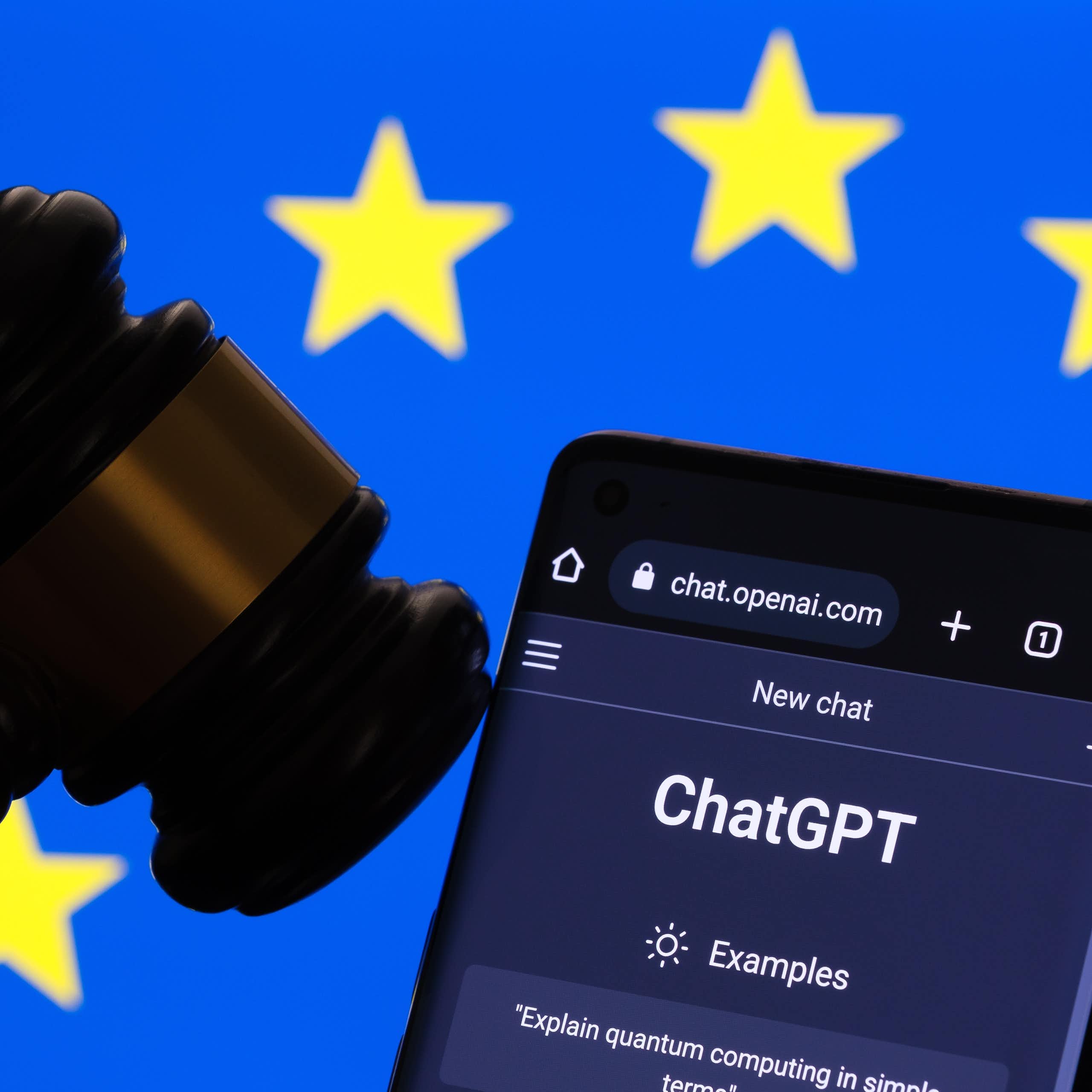 Le site internet de ChatGPT ouvert sur un téléphone, à côté d'un maillet de juge, devant un drapeau européen.