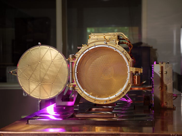 A metal instrument with a round door that opens to reveal a mesh screen to collect dust.