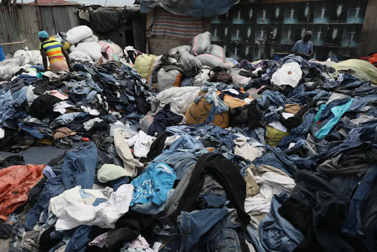 D'énormes piles de vêtements forment des montagnes que les gens traversent en regardant les vêtements