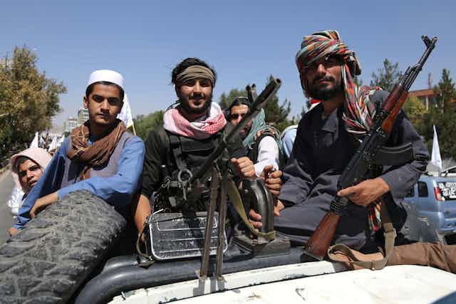 Members of the Taliban sitting on a truck with guns.