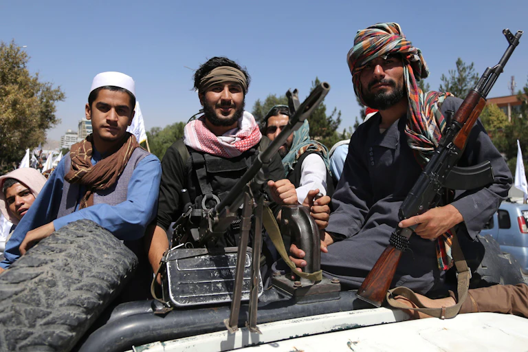 Members of the Taliban sitting on a truck with guns.