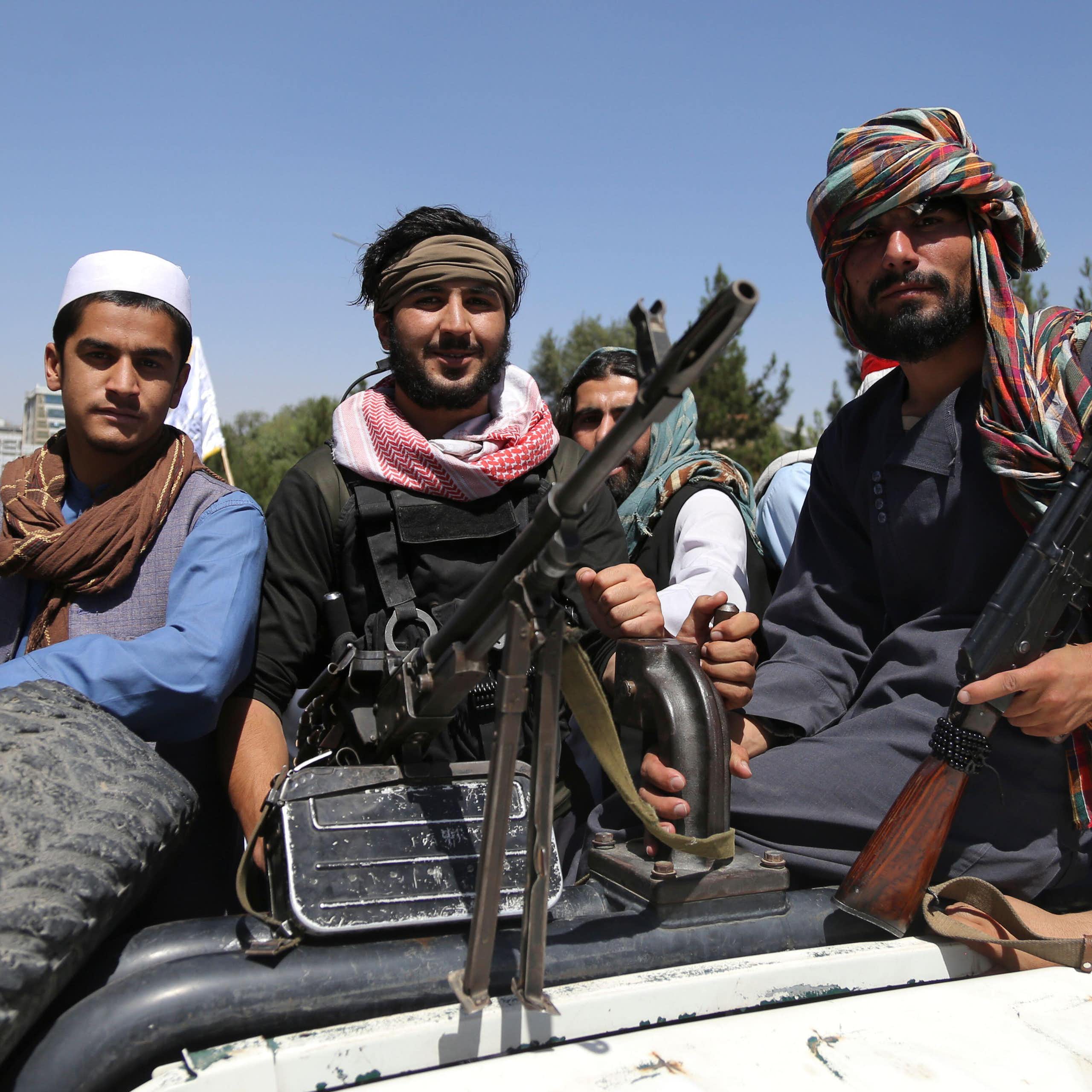 Members of the Taliban sitting on a truck with guns.