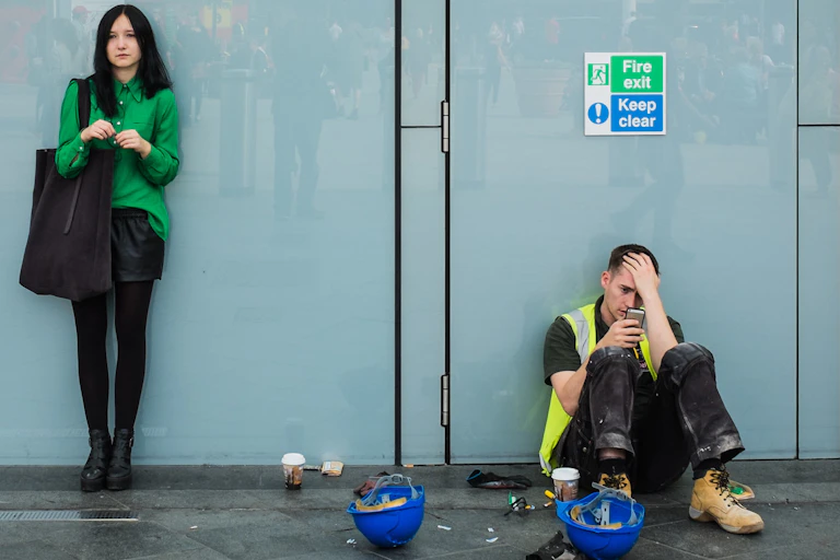Young woman and construction worker next to one another against a glass panel