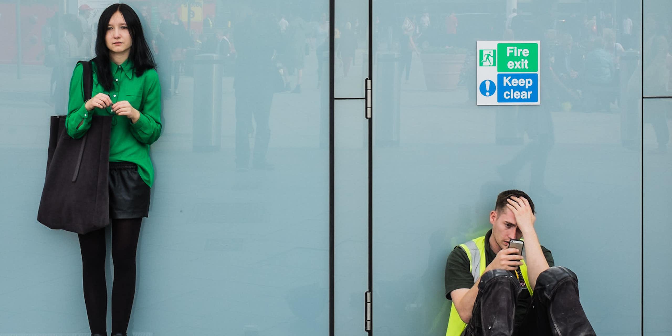 Young woman and construction worker next to one another against a glass panel