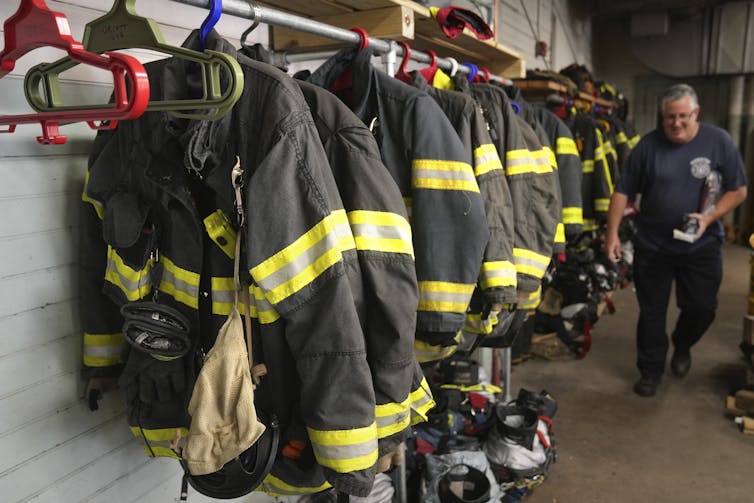 A firefighter walks past a row of firefighter gear.