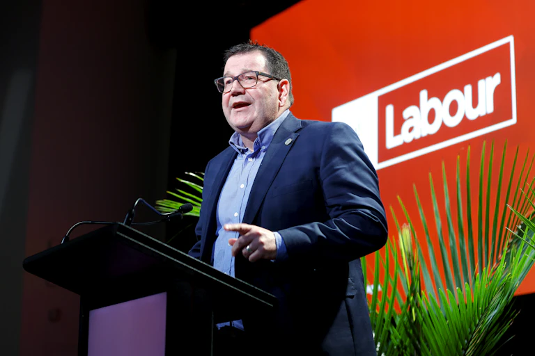 Gratn Robertson speaking in front of a Labour sign