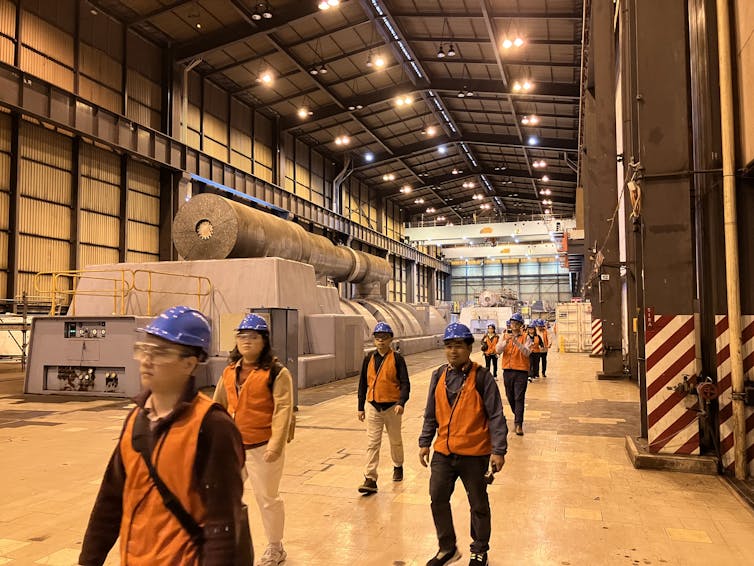 A group of people wearing hi-vis vests and blue hard hats touring through Yallourn Power Station