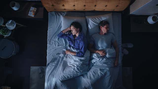 A woman and a man sleep in their bed.