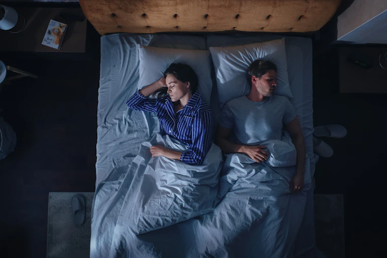 A woman and a man sleep in their bed.