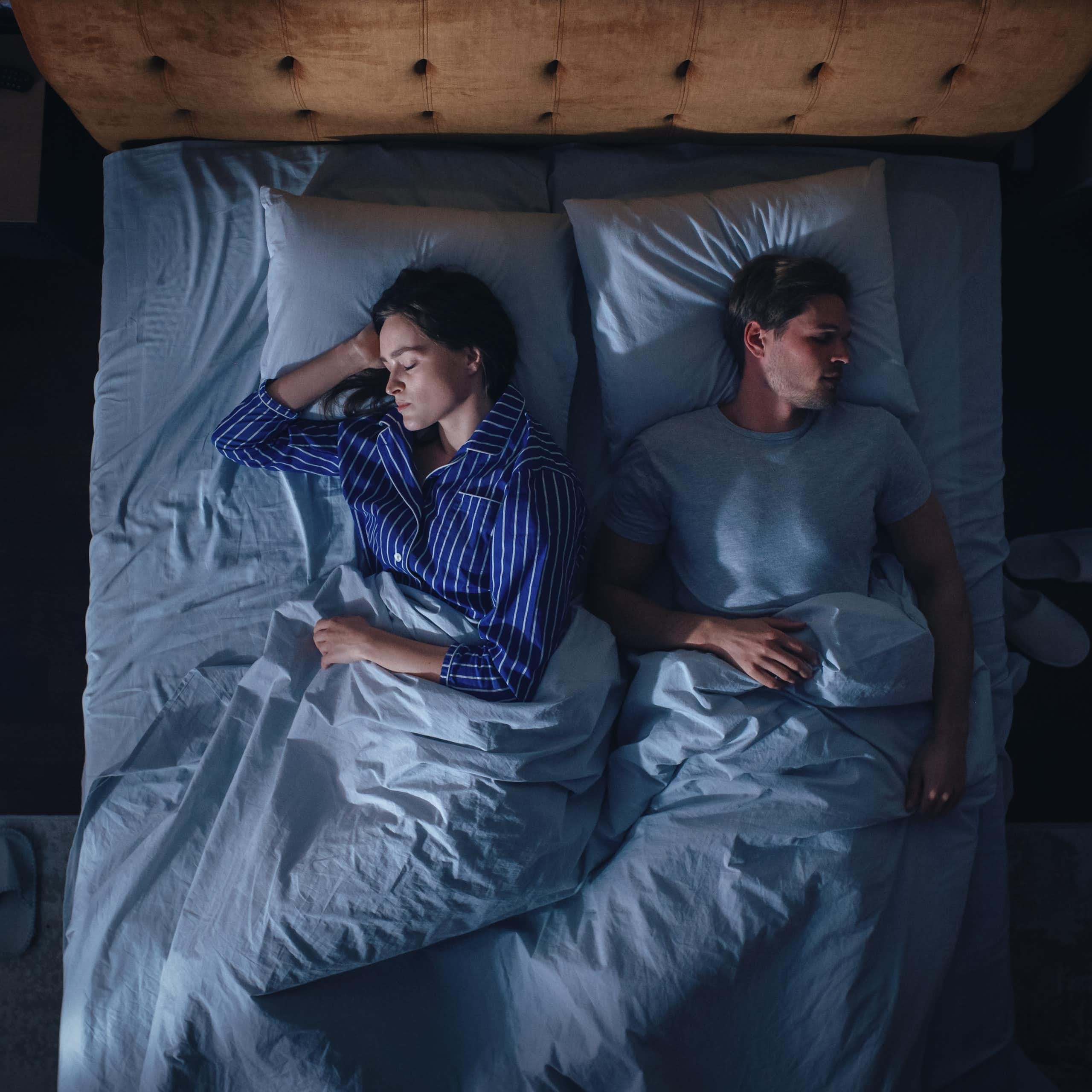A woman and a man sleep in their bed.