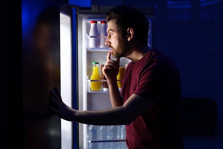 A man looks for a midnight snack in his fridge.