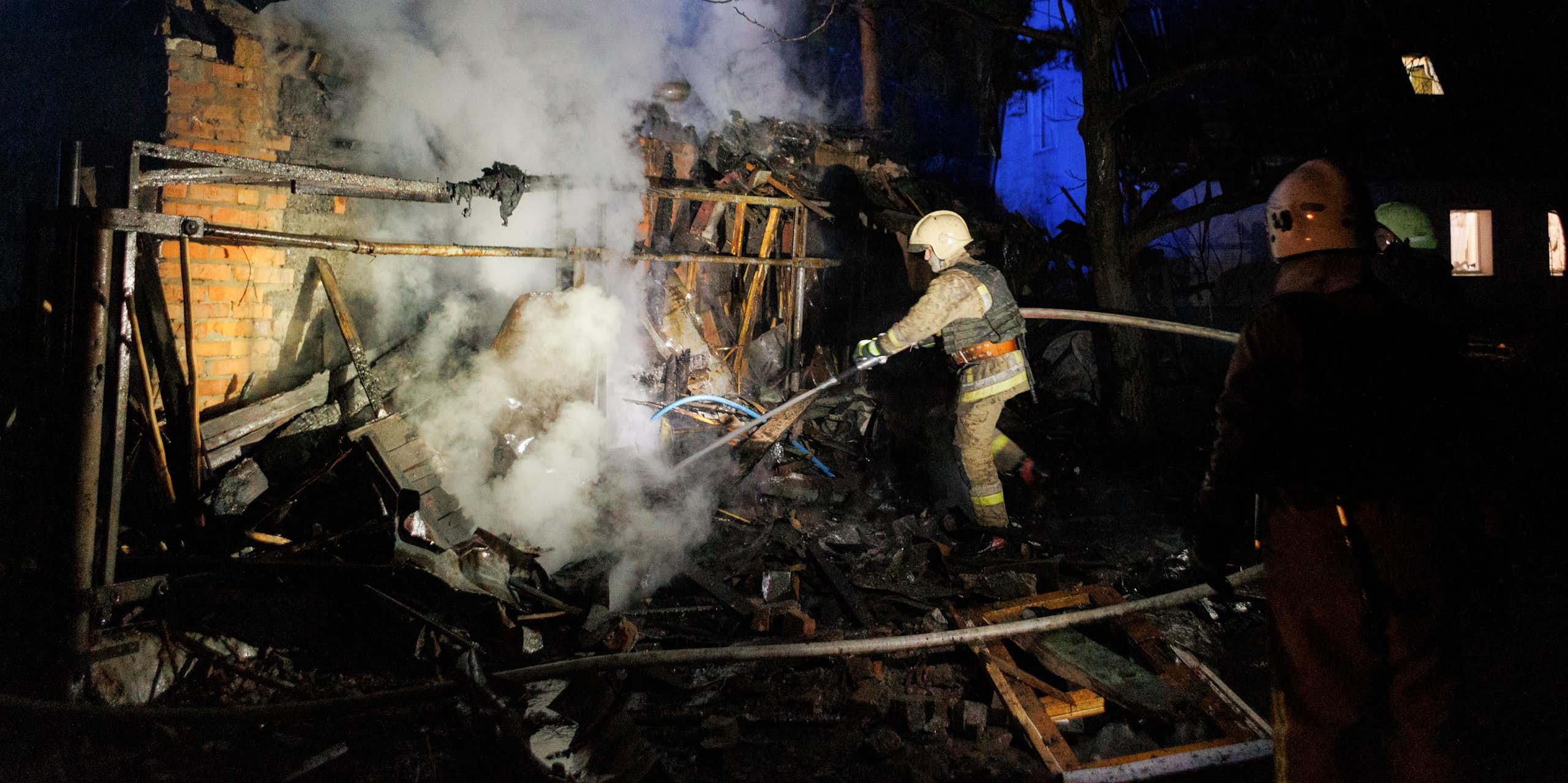 A firefighter tries to extinguish a blaze in a bombed building.