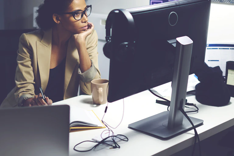 A young women staring at a computer screen with her chin in her hand.