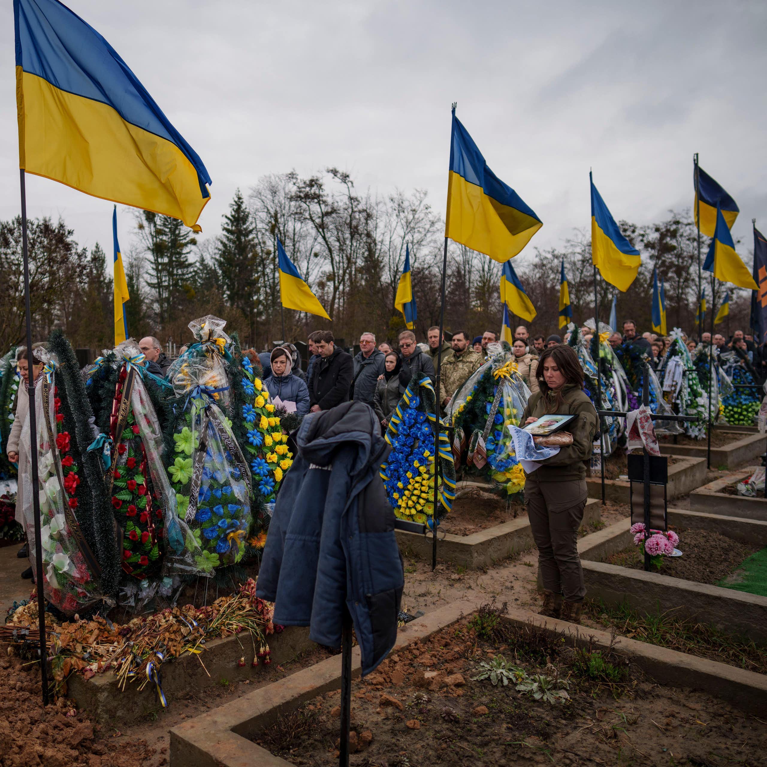 People throw dirt into the grave at the funeral of a Ukrainian soldier.