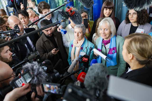 Two women surrounded by journalists