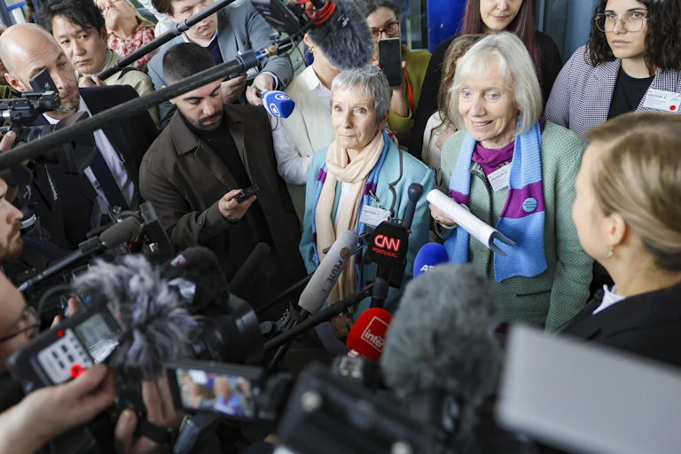 Two women surrounded by journalists