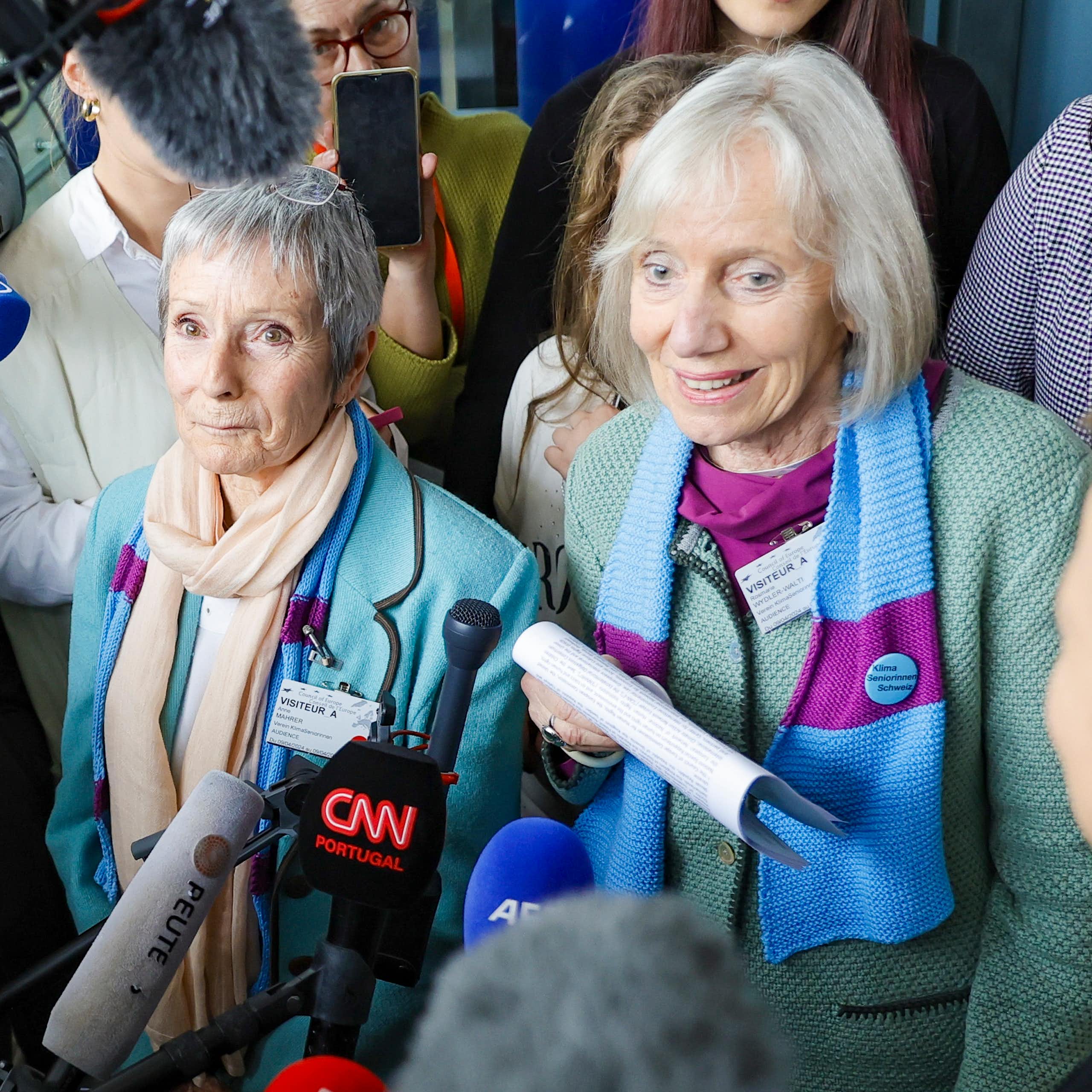 Two women surrounded by journalists
