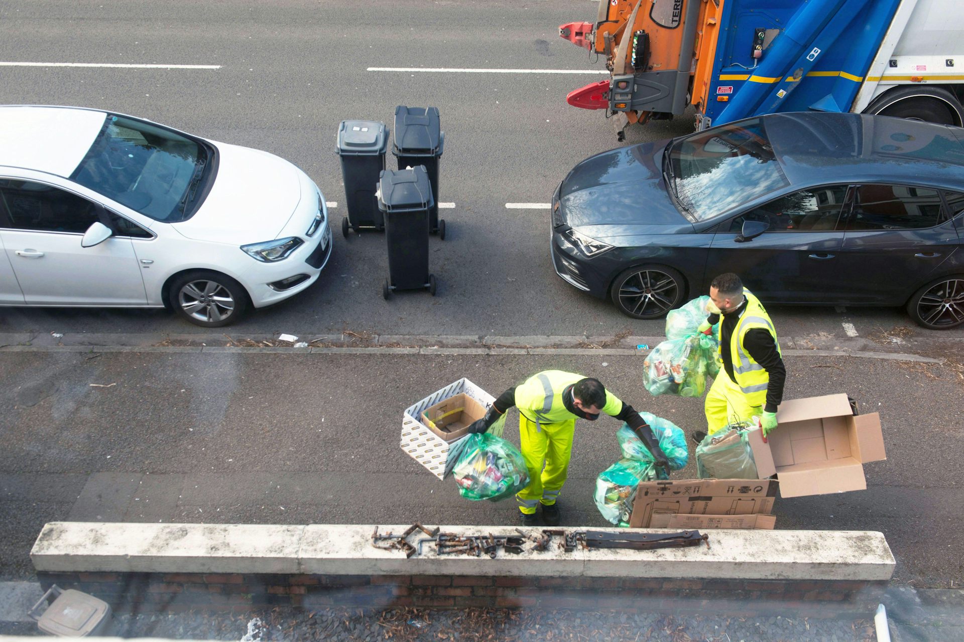 Two refuse workers on a street.