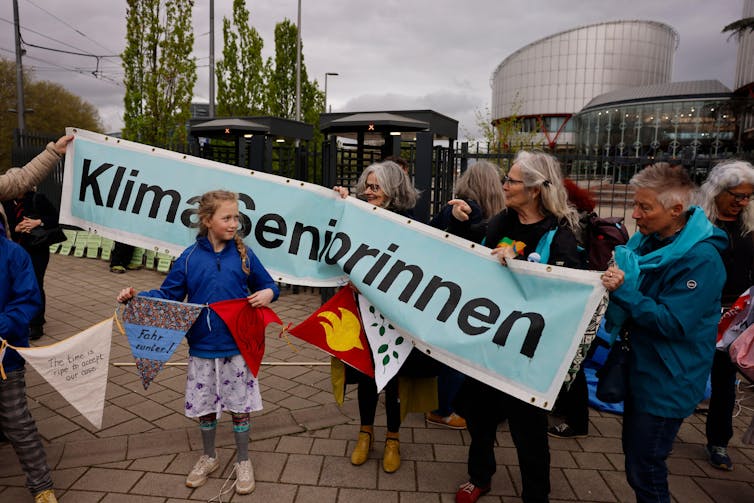 Girl stands in front of KlimaSeniorinnen banner