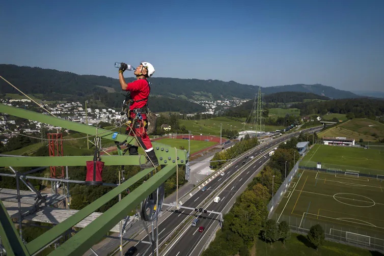 Thirsty construction worker on hot day above Swiss valley