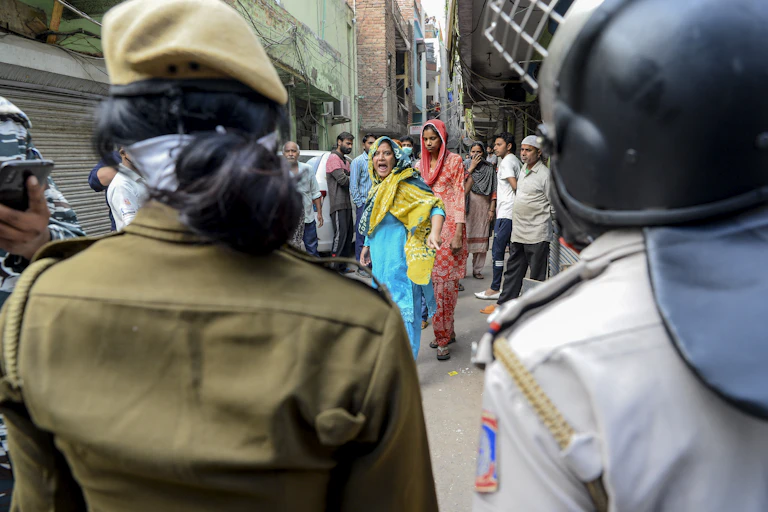 Woman dressed in blue and yellow screams at security personnel.
