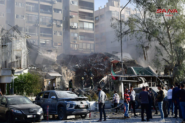 A small crowd of people inspect a damaged building.