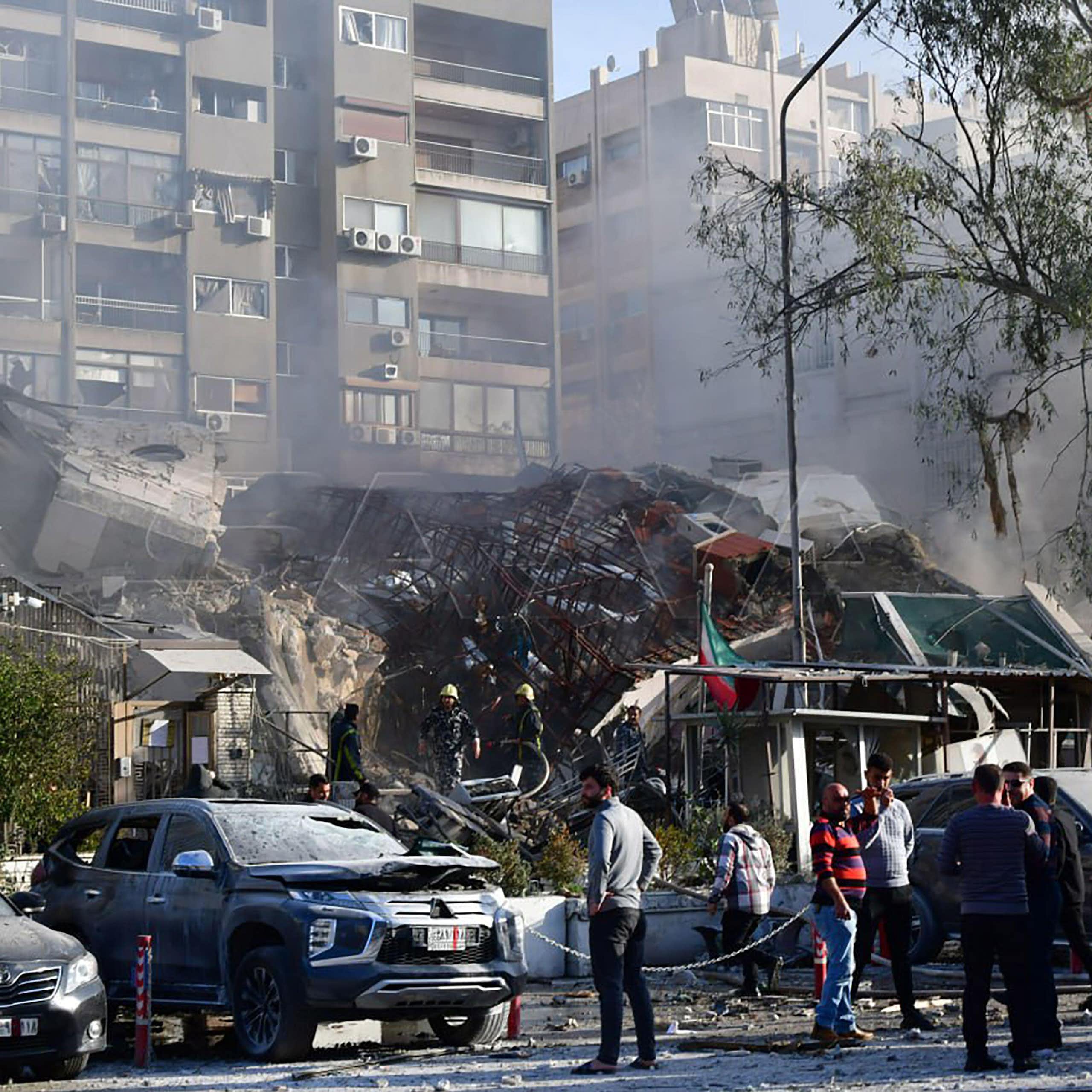 A small crowd of people inspect a damaged building.