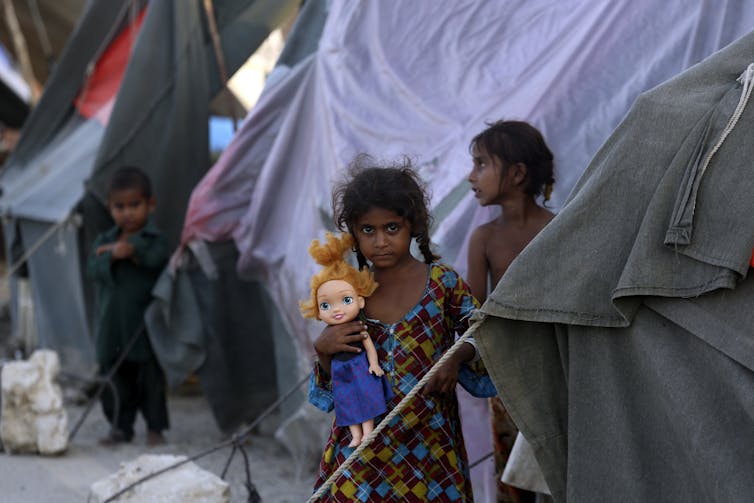 Children stand next to tents.