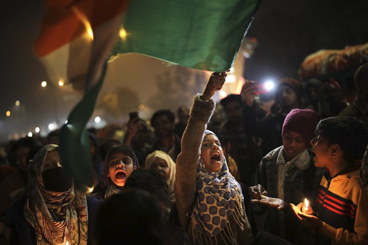 As meninas agitam a bandeira nacional indiana e gritam à noite.