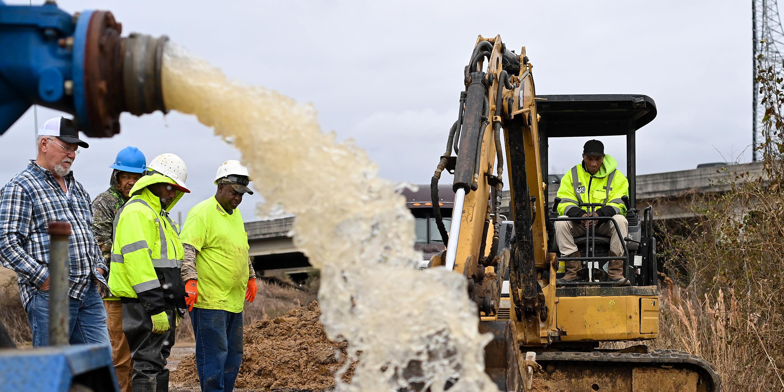 Water gushes from a pipe draining a work area as workers try to figure out how to fix a broken water main.