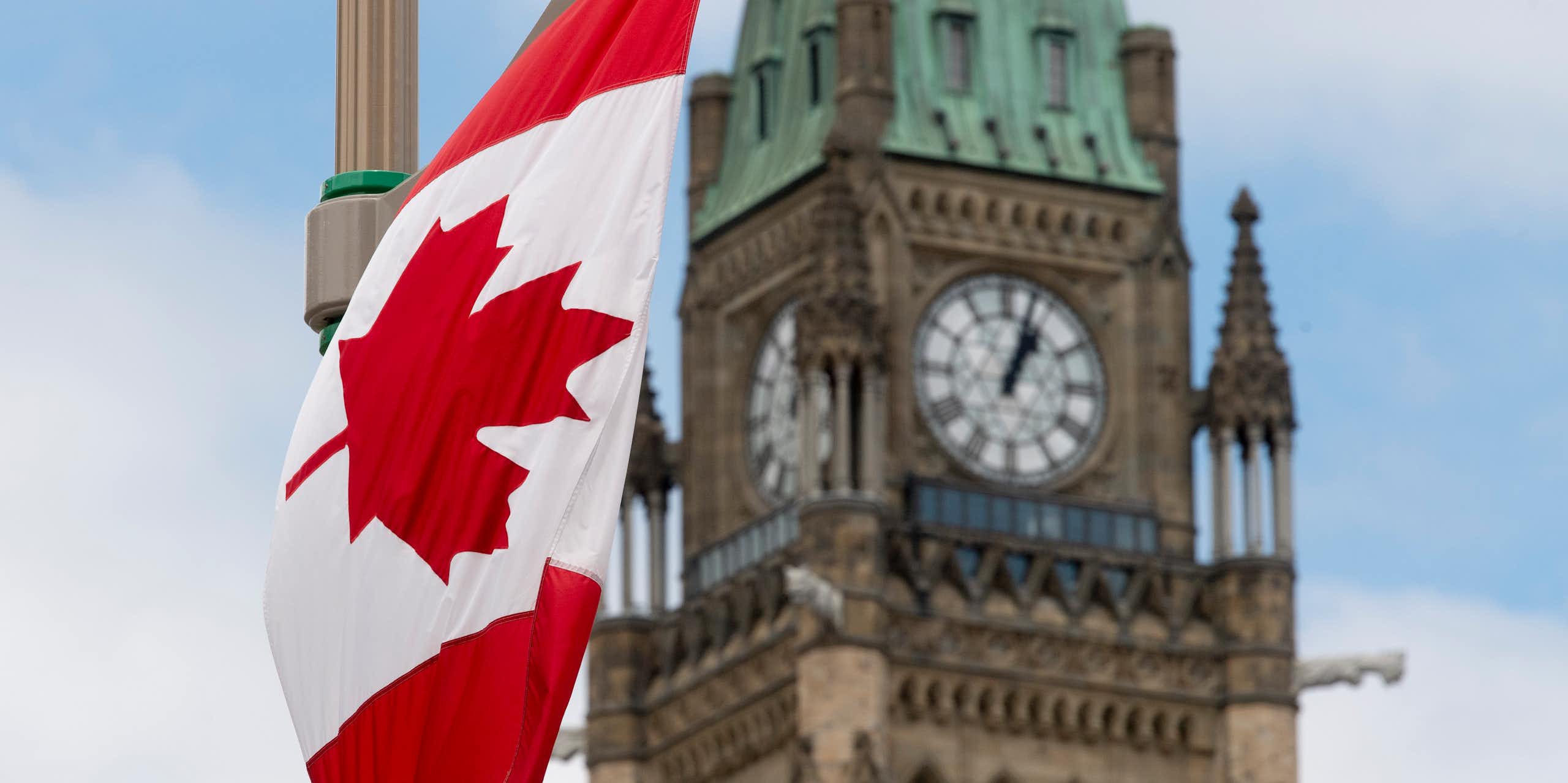 A Canadian flag hands in front of a clock tower