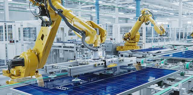 Robots assemble solar panels in a factory assembly line