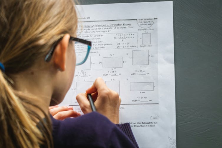 A girl answers questions about perimeter calculations on a maths work sheet.