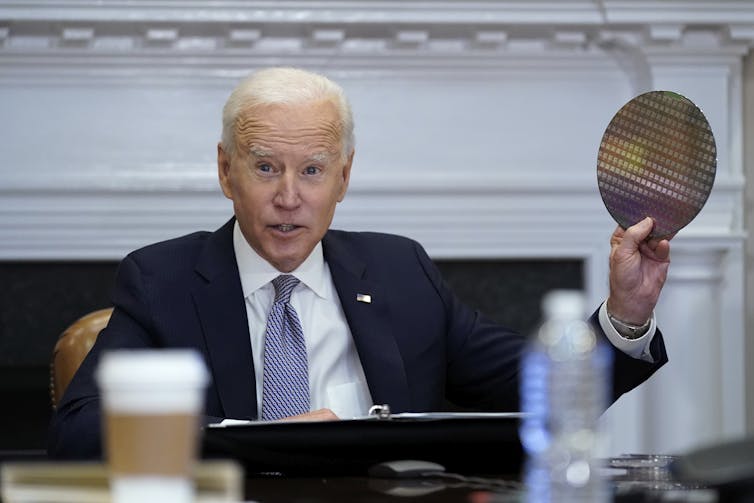 US President Joe Biden holds up a silicon wafer, used in the manufacter of advanced semiconductors